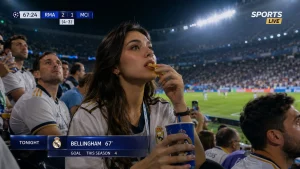 Cena de reação de fãs em transmissão esportiva com inteligência artificial em um estádio, com gráficos ao vivo da partida e refletores.